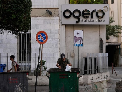 A man scavenges in the garbage next to a building of the state-owned telecom and internet company, Ogero, in Beirut.