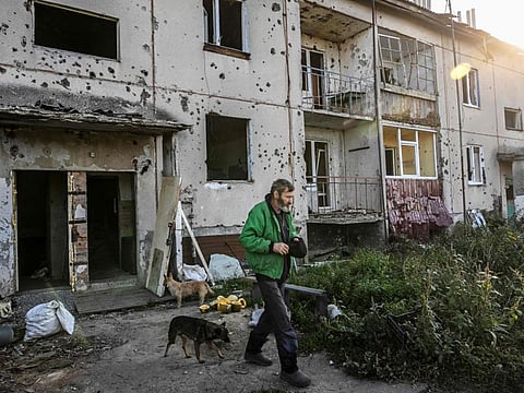 A man walks past a damaged building in Hrakove village in September 9, 2022.  