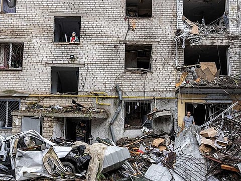 People stand on debris of a residential building destroyed by a strike, amid Russia's attack of Ukraine, in Mykolaiv, Ukraine, September 11, 2022. 