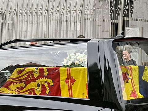 The hearse carrying the coffin of Queen Elizabeth II, draped in the Royal Standard of Scotland, is driven through Edinburgh towards the Palace of Holyroodhouse.