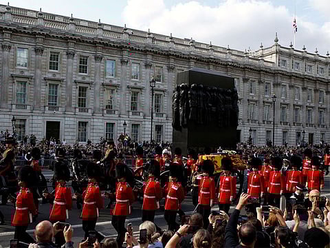 The coffin of Queen Elizabeth II flanked by Grenadier Guards and the King's Troop Royal Horse Artillery is pictured by onlookers along Whitehall during a procession from Buckingham Palace to Westminster Hall in London.