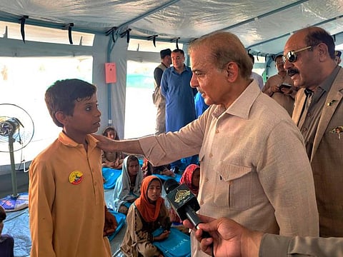 Prime Minister Shehbaz Sharif talks to a student at a makeshift school inside a tent in the flood-hit area of Suhbatpur in Balochistan on Wednesday. 