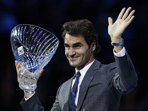 Roger Federer waves as he holds up the 2013 "Fans' Favourite" trophy awarded to him at the ATP World Tour Finals.