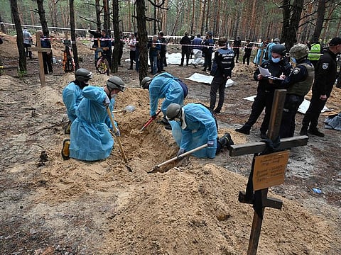 Forensic technicians dig a grave in a forest on the outskirts of Izyum, eastern Ukraine on September 16, 2022.  
