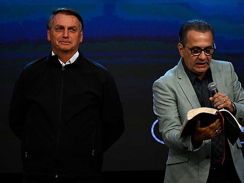 Brazilian President and re-election candidate Jair Bolsonaro (L) listens to Pastor Silas Malafaia reading during a ceremony to celebrate Malafaia's birthday at the Assembly of God evangelical church in Rio de Janeiro, Brazil, on September 15, 2022. 