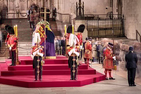 A long exposure photograph shows members of the public as they file past the coffin of Queen Elizabeth II, draped in the Royal Standard with the Imperial State Crown and the Sovereign's orb and sceptre, lying in state on the catafalque in Westminster Hall at the Palace of Westminster in London on September 15, 2022. 