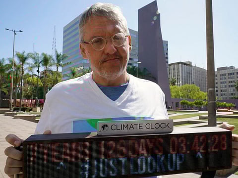 Adam McKay, director of the film "Don't Look Up," holds a Climate Clock as he joins members of the Youth Climate Los Angeles coalition and others protesting climate change at Pershing Square in Los Angeles, Friday, March 18, 2022.