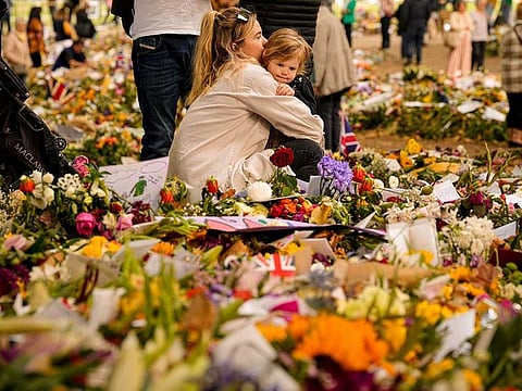 People bring floral tributes to Queen Elizabeth II, the day after her funeral in London's Green Park, Tuesday, Sept. 20, 2022. 