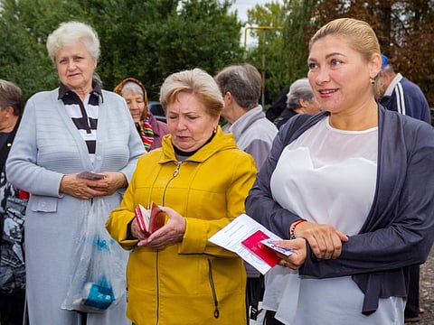 People gather to attend voting in a referendum in front of a mobile polling station in Krasny Yar village outside Luhansk, eastern Ukraine, on September 23, 2022.  