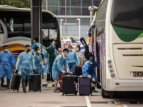 Workers load travellers' luggage onto a bus at Hong Kong International Airport before taking them to hotel quarantine on September 23, 2022. 