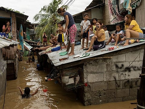 Residents wait on the roof of their homes, for flooding to subside after Super Typhoon Noru, in San Miguel, Bulacan province, Philippines.