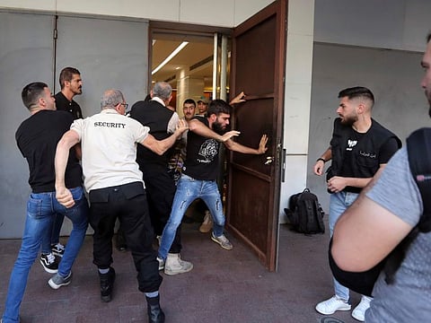 Security guards try to stop security personnel members from entering a BLOM bank branch, in the southern port city of Sidon, Lebanon, Monday, Sept. 26, 2022.