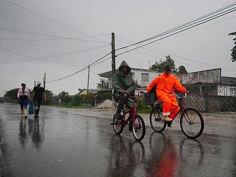 People walk under the rain ahead of the arrival of Hurricane Ian in Coloma, Cuba, September 26, 2022. 