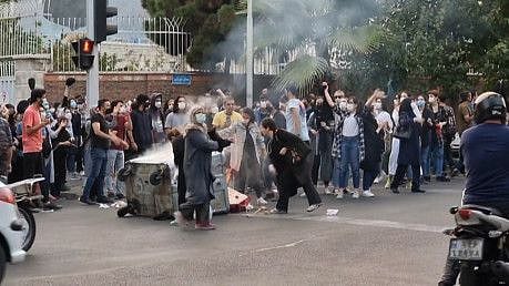 Iranian demonstrators burning their headscarves and setting fire to a trash bin in the capital Tehran. 