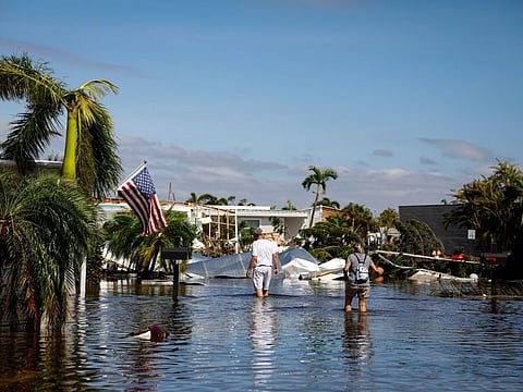 People walk on a flooded street at a trailer park following Hurricane Ian in Fort Myers, Florida, on September 29, 2022. 