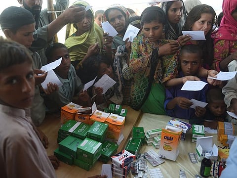 Women and Children displaced by floods wait for medicine at a makeshift medical camp in Dadu district, Sindh province, on September 27, 2022. 