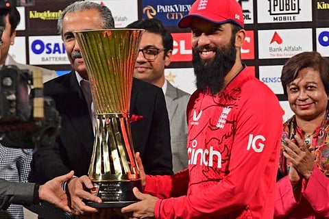 England's captain Moeen Ali (right) holds the trophy after winning the series at the end of the seventh Twenty20 international cricket match against Pakistan at the Gaddafi Cricket Stadium in Lahore.