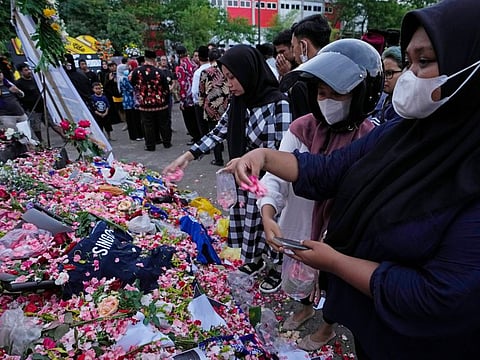 Supporters of soccer club Arema FC throw flowers for victims of Saturday's soccer match stampede outside the Kanjuruhan Stadium in Malang, Indonesia, Monday, Oct. 3, 2022.