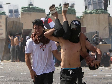 A wounded protester is carried during clashes with Iraqi security forces at a gathering marking the third anniversary of the anti-government protests in Baghdad, Iraq October 1, 2022. 