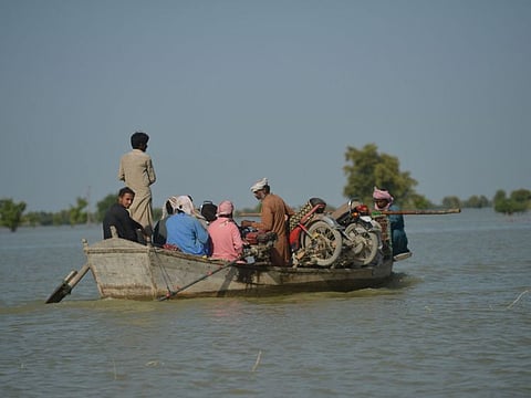 Internally displaced people use boats to cross the flooded area in Dadu district, Sindh province, on September 27, 2022. 