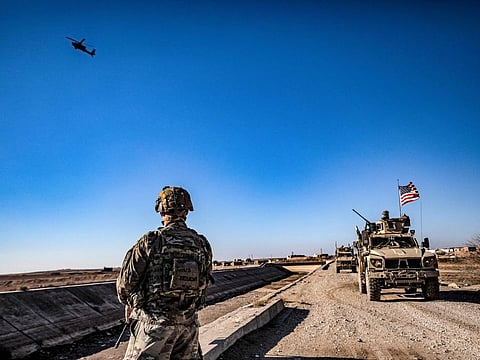 A US AH-64 Apache attack helicopter flies above US soldiers patrolling along the frontlines between areas held by the Syrian Democratic Forces (SDF) and Turkish-backed fighters near the village of Dardara in the countryside of Tal Tamr in Syria's northeastern Hasakeh province.  