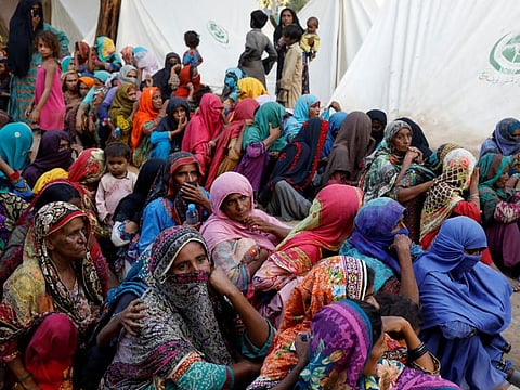 Displaced people wait to receive food handouts in Sehwan.