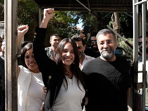 Sali Hafez, centre, who broke into a BLOM Bank branch last month with others activists and forced bank employees to hand over $12,000 and the equivalent of about $1,000 in Lebanese pounds gestures as she leaves the Justice Palace, in Beirut on Oct. 6, 2022.  