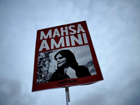 A woman holds a placard with a picture of Iranian Mahsa Amini as she attends a protest against her death, in Berlin.