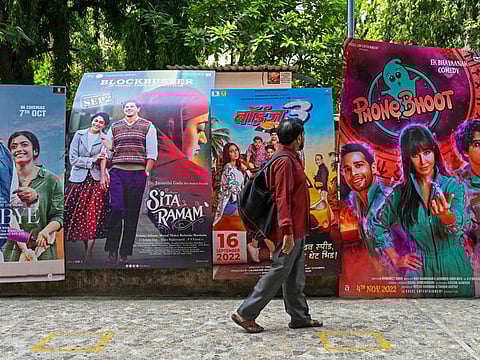 In this picture taken on October 1, 2022, a moviegoer walks past movie posters displayed outside the G7 multiplex in Mumbai.
