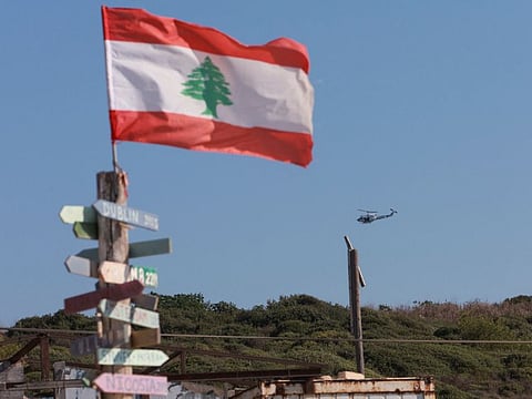 An aircraft flies past as signs bearing names of cities are seen in Naqoura, near the Lebanese-Israeli border, southern Lebanon, October 11, 2022. 