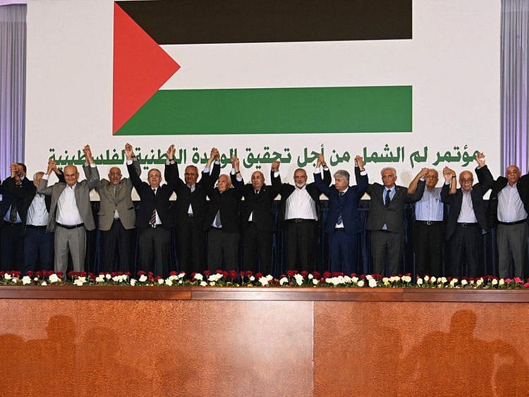 A handout picture provided by the Algerian Presidency's official Facebook Page shows Algerian President Abdul Madjid Tebboune with members of Palestinian factions upon signing an inter-Palestinian reconciliation deal in the capital Algiers.