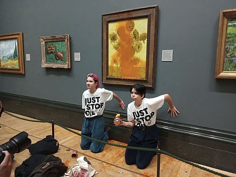 Handout photo issued by Just Stop Oil of two protesters who have thrown tinned soup at Vincent Van Gogh's famous 1888 work Sunflowers at the National Gallery in London, on October 14, 2022.  