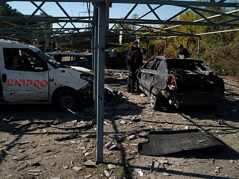 Police officers work at a site where several cars were damaged after a Russian attack in Zaporizhzhia, Ukraine, Saturday, Oct. 15, 2022.