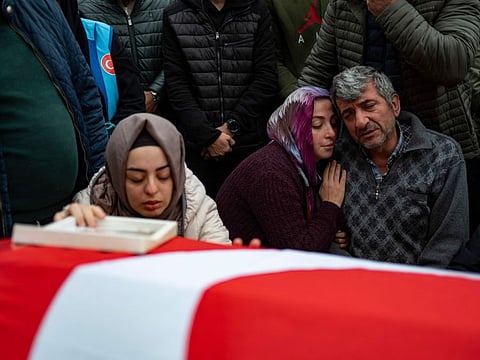 The pregnant wife of Saban Yildirim grieves over his flag covered coffin, as his father and close relative sit near by, during his funeral following the death of dozens of miners two days ago in an explosion in a coal mine in the town of Amasra in the Black Sea province of Bartin on October 16, 2022. 