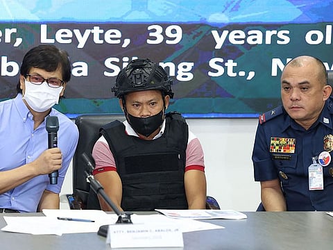 Joel Estorial (C), the alleged gunman in the killing of Philippine journalist Percival Mabasa, is presented to the media as Philippine Interior Secretary Benjamin Abalos (L) speaks during a press conference at the national police headquarters in Manila on October 18, 2022. 