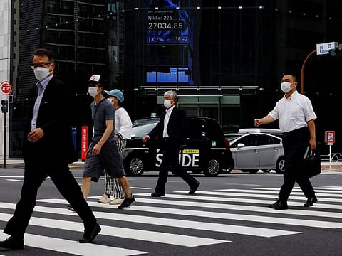 People pass by an electronic screen showing Japan's Nikkei share price index. Of the Nikkei components, 91 stocks rose and 121 declined, while 13 were flat.
