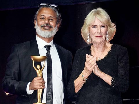 Sri Lankan writer Shehan Karunatilaka (left) poses next to Britain's Camilla, Queen Consort after winning the British Booker Prize for his novel "The Seven Moons of Maali Almeida", during the Booker Prize for Fiction 2022 awards ceremony, in London, on October 17, 2022. 