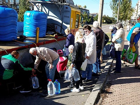 Local people fill up bottles with fresh drinking water, as the main supply pipeline for drinking water for the city was damaged in Kherson region at the beginning of Russia's attack on Ukraine, in Mykolaiv, Ukraine October 16, 2022.  