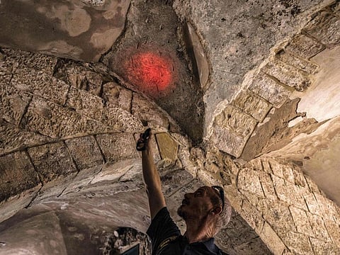 Shai Halevi, archaeologist of the Israel Antiquities Authority (IAA), illuminates a graffiti bearing the name of Adrian von Bubenberg, a Swiss knight who was military commander and mayor of Bern in the 15th century and who had undertaken a 1466 pilgrimage to Jerusalem, during their archaeological survey of a wall at the "King David Tomb Complex" on Mount Zion outside the old city walls of Jerusalem on October 20, 2022. 