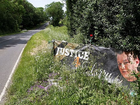 A banner and a memorial area for British teenager Harry Dunn who died in a road traffic collision is pictured near to the entrance of RAF Croughton, near Brackley, on June 11, 2021.  