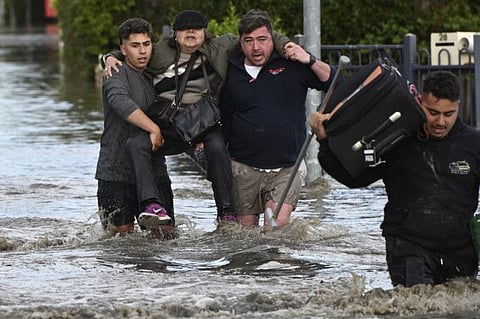 A woman is rescued from floodwaters in Melbourne, Australia's suburb of Maribyrnong, on October 14, 2022.  The floods, which began last week, have claimed five lives, prompted thousands of requests for assistance and led to hundreds of people being rescued from rising waters.
