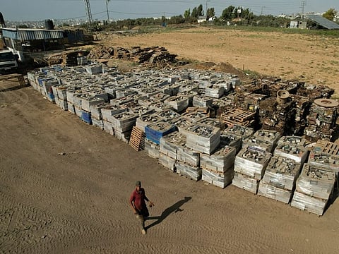 A Palestinian worker walks near broken batteries collected for sale and export, in Gaza Strip October 16, 2022.