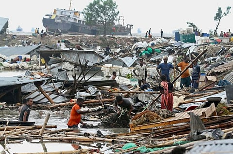 Residents search for their belongings amid the debis of their collapsed huts after the cyclone Sitrang hits in Chittagong on October 25, 2022.