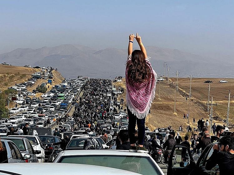 This UGC image posted on Twitter reportedly on October 26, 2022 shows an unveiled woman standing on top of a vehicle as thousands make their way towards Aichi cemetery in Saqez, Mahsa Amini's home town in the western Iranian province of Kurdistan, to mark 40 days since her death, defying heightened security measures as part of a bloody crackdown on women-led protests. 
