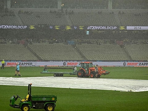 Ground staff cover the field as rain delays the start of play during the ICC men's Twenty20 World Cup 2022 cricket match between New Zealand and Afghanistan and Ireland at Melbourne Cricket Ground (MCG) in Melbourne.