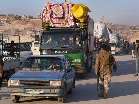 Lebanese soldiers pass next of trucks convoy that carry Syrian refugees and their belongings, at a gathering point where they prepare to cross the border back home to Syria, in the eastern Lebanese border town of Arsal, Lebanon, on October 26, 2022.  