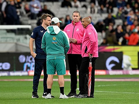 England skipper Jos Buttler and Australia's Aaron Finch interact with the umpires during the rain delay before the start of their Group 1 clash in Melbourne on Friday. Match abandoned without a ball being bowled due to rain.