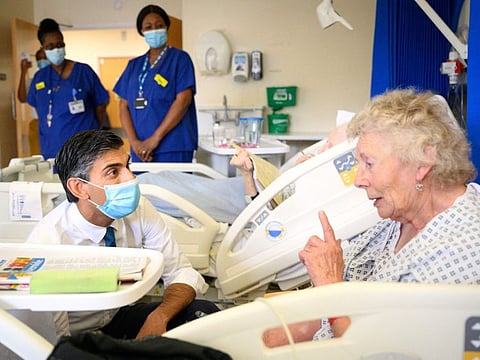 Britain's Prime Minister Rishi Sunak  speaks with patient Catherine Poole during his visit to Croydon University Hospital in south London on October 28, 2022.  