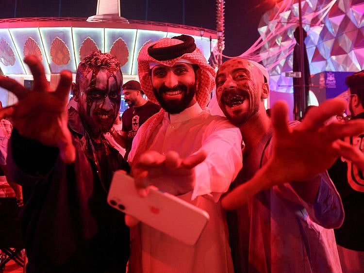 A Saudi man takes a photo with people dressed in costumes to celebrate Halloween during "Scary Weekend Event" at Boulevard, during Riyadh Season in Riyadh, October 28, 2022.  
