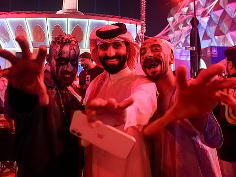 A Saudi man takes a photo with people dressed in costumes to celebrate Halloween during "Scary Weekend Event" at Boulevard, during Riyadh Season in Riyadh, October 28, 2022.  